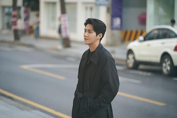 這一套造型，金宣虎幾乎以「全黑」作為唯一語言，長版黑色大衣線條俐落、比例修長，搭配內層同色系單品，透過材質與層次的細微差異，讓黑色呈現出深淺變化，而不是單一塊面。