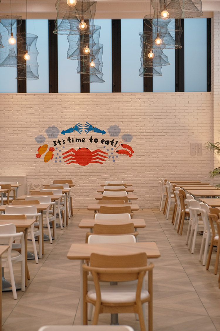  ​ 餐廳以函館港口城市為靈感，透過烏賊墨藝術牆、漁網燈飾與藍色系空間設計營造海洋氛圍。旅人可在此一邊享用早餐，一邊感受廚房熱氣與港灣氣息交織的節奏。