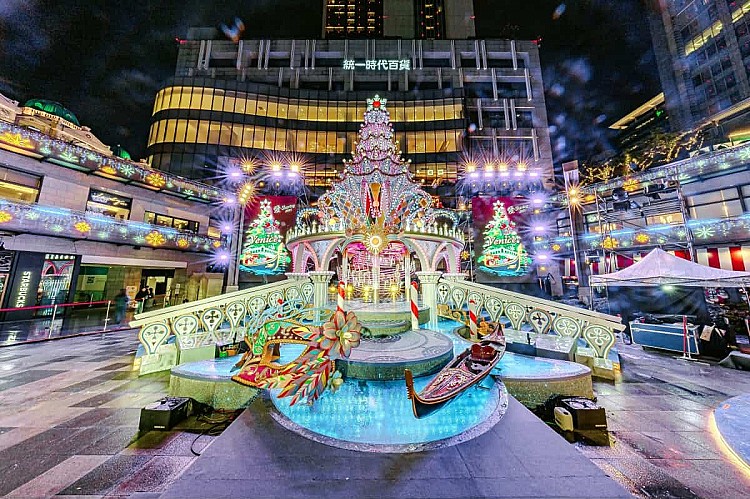 每年同樣備受矚目的統一時代百貨,這次也在二樓夢廣場打造「威尼斯」主題的浪漫場景,高達 13 公尺的主樹以紫光與金色線條營造優雅氛圍,周邊結合義大利水都風情打造總督宮、拱橋、水道與貢多拉船造景,夜晚還有水幕燈光秀與飄雪效果,讓整個空間在夜色中更添夢幻氛圍。