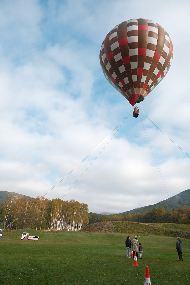 隨著熱氣球緩緩升空，腳下的牧場與森林漸行漸遠，山谷的全貌在眼前徐徐展開，層疊山巒與清晨光影交織出壯麗景致。