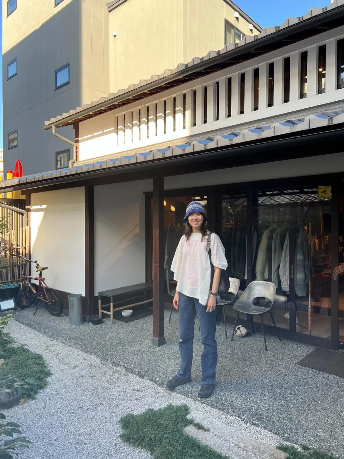 孔曉振以白色泡泡感短袖上衣搭配深藍色直筒牛仔褲，戴上藍色針織漁夫帽站在日式木造店門口拍照