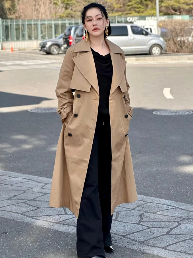 立秋過後，雖然白天依舊帶著夏日餘溫，但晚上漸漸吹起微涼的風，此時一件兼具保暖與時髦感的長風衣，便成了換季衣櫥裡不可或缺的存在。站在街頭的小S，身穿一襲經典駝色雙排扣長風衣，內搭全黑造型，再以金屬感大耳環點綴細節，整體造型俐落而充滿力量。隨著步伐擺動的風衣衣襬，不僅展現優雅線條，也讓經典單品散發歷久彌新的魅力。