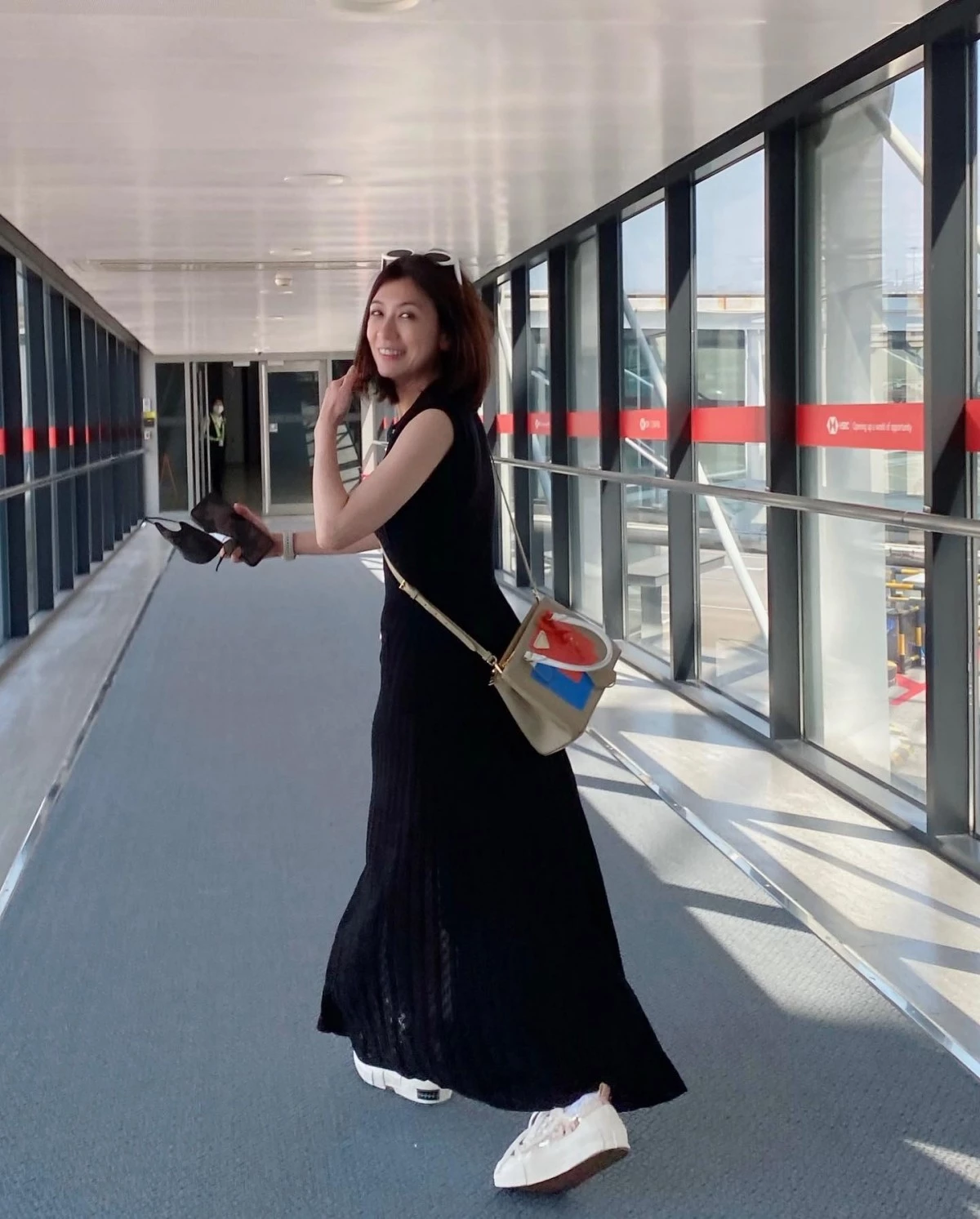 賈靜雯在機場以黑色針織長洋裝搭配白色厚底小白鞋,斜背拼色小方包、頭戴墨鏡,用球鞋中和長洋裝的優雅、輕鬆好走。