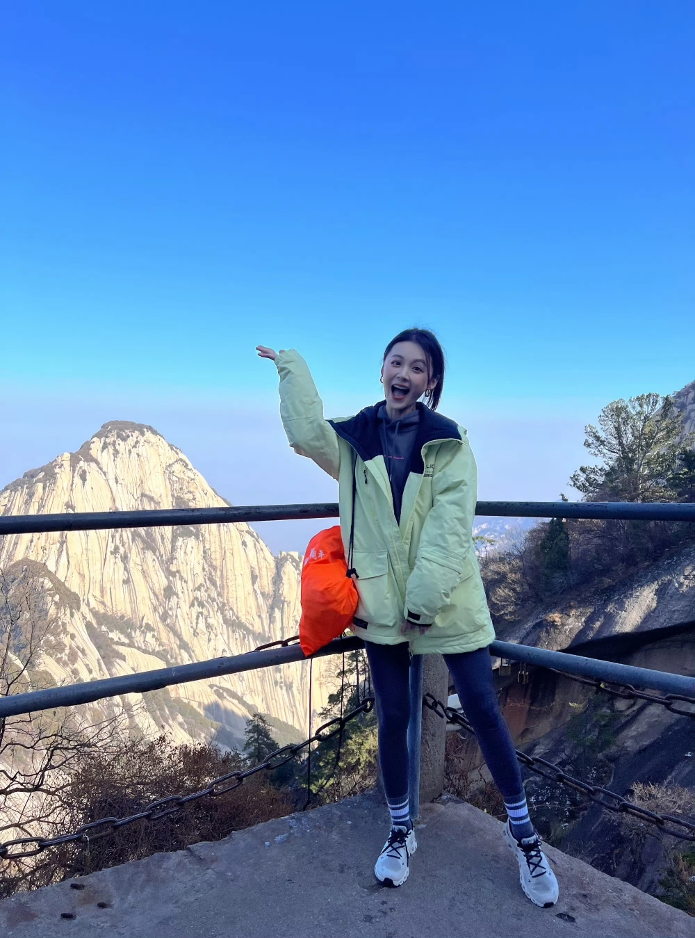 40歲毛林林登上華山,以螢光黃綠連帽衝鋒衣內搭黑色帽T,下身配深色緊身內搭褲與白襪,腳踩白色On昂跑球鞋,機能登山也時髦。