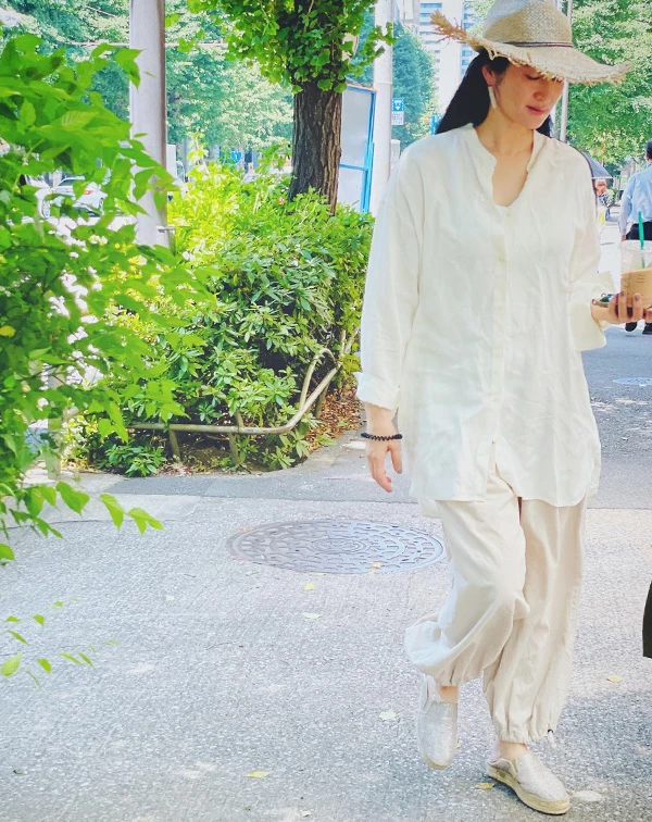 寬鬆的純白微透亞麻襯衫,搭配米杏色束口寬褲、草編鞋,再戴上一頂帶有隨性流蘇邊緣的寬檐草帽。小雪這身質樸自然的穿搭,完美詮釋了半退休田園生活的愜意與舒暢,充滿了清爽的夏日氣息。