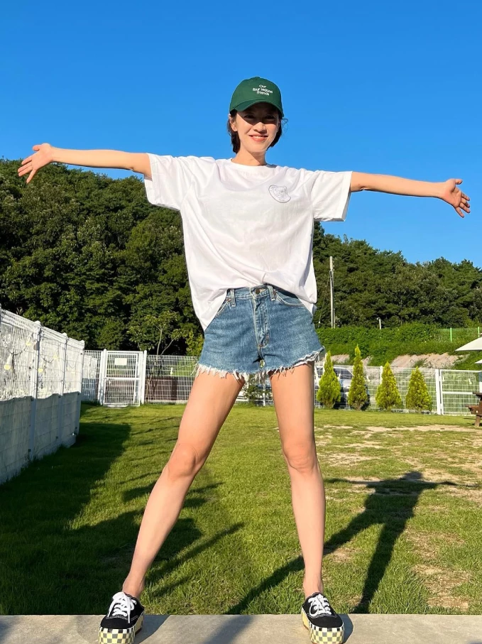 這張照片裡的宋智孝，活脫就像一位充滿活力的陽光少女！她選擇了最基礎、不會出錯的夏日組合：白T＋丹寧短褲。再戴上一頂綠色棒球帽，腳踩帆布鞋，整個人散發出無敵的青春元氣。  運動休閒風，是我們減齡的最快捷徑。即使是基礎款的白T和丹寧褲，也要選擇有質感、有設計細節的單品（如磨邊、特殊圖案），看上去會更時髦。