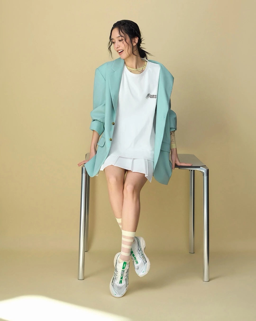 陳庭妮以薄荷綠 oversized 雙排釦西裝疊搭白色 asics T-shirt 與白色百褶短裙，腳踩 asics GT-2160 BREEZE 白綠雙拼球鞋