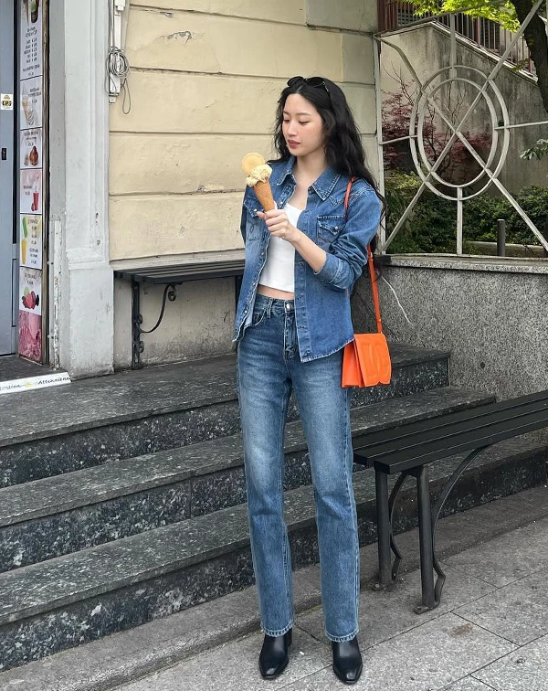 文佳煐以白色短版背心外搭深藍色丹寧襯衫，下身穿著經典直筒牛仔褲，腳踩黑色短靴，並巧妙用亮橘色肩背包點綴整套造型。這種「全身丹寧」的層次感，加上撞色配件的點睛之筆，把日常休閒穿出了高質感的街拍範兒。
