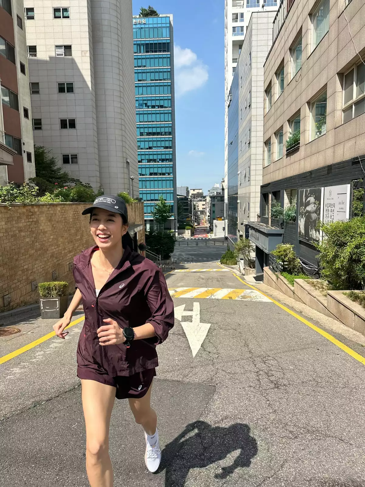 陳庭妮以全套酒紅色 asics 機能跑步套裝現身首爾街頭，短袖夾克搭同色系機能短褲，戴上黑色 asics 鴨舌帽與白色跑鞋
