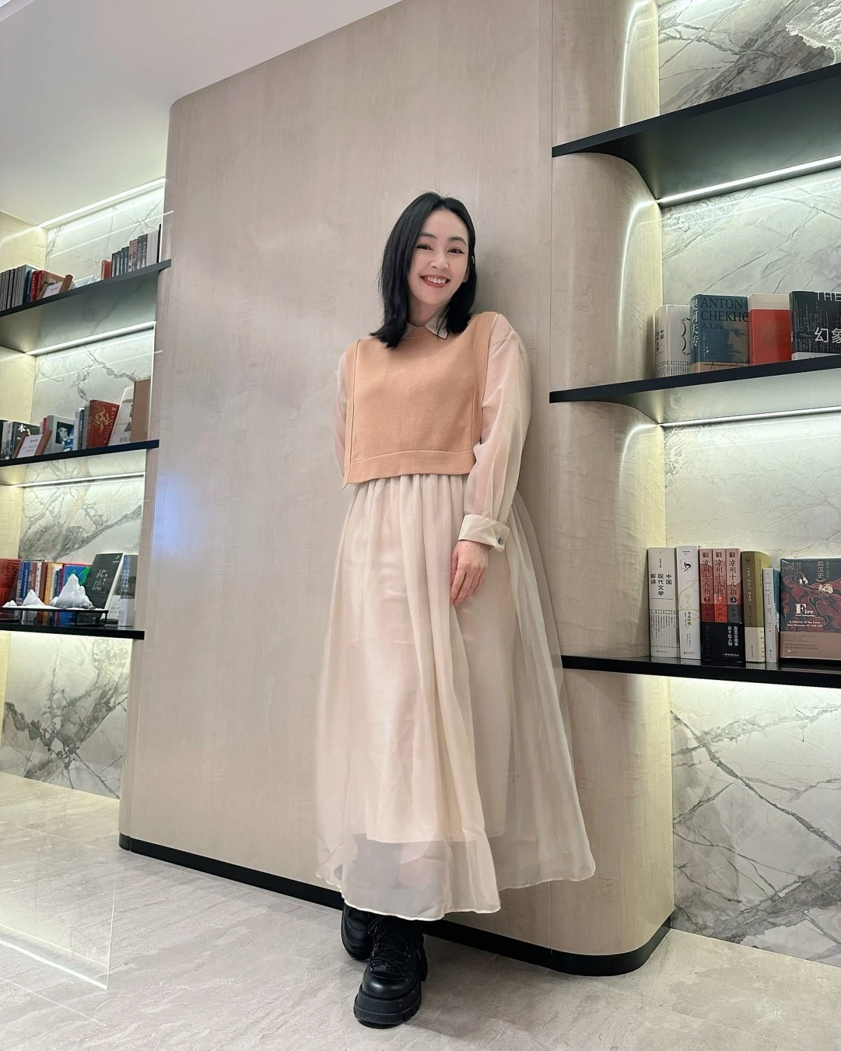 蔡燦得以杏色短版針織背心疊穿膚色透紗長袖洋裝,長紗袖蓋住手臂、遮蝴蝶袖,腳踩黑色短靴,柔美又減齡。