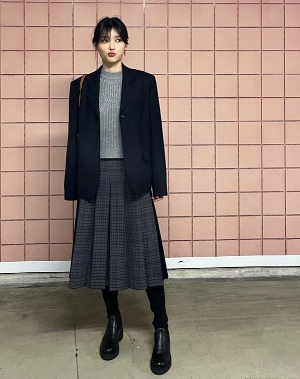 秋冬季節想要穿出減齡又具備知性美的學院風，以「深色西裝外套 + 針織衫 + 格紋百褶裙」作為搭配公式絕對不出錯。 百褶裙的長度，建議選擇及膝或過膝的款式，能讓整體比例更顯沉穩；搭配黑色短靴或長靴時，可以露出微微的腿部線條或搭配深色褲襪，為造型注入更多層次感。