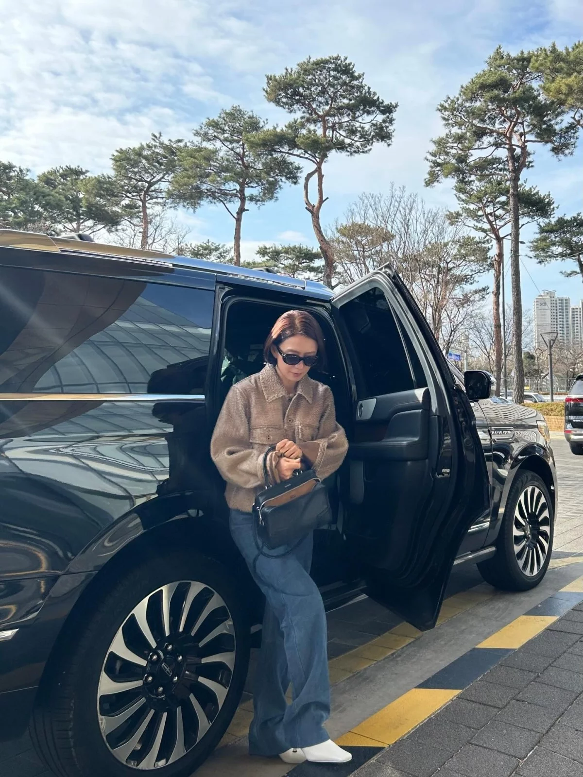 金喜愛以米色泰迪絨襯衫式外套搭配淺藍色寬版牛仔褲,腳踩白色短靴、手拿Loewe黑色手袋,暖冬造型俐落又減齡。