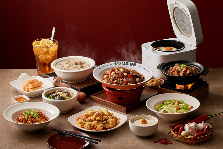 湘菜品牌「炒湘湘」推出新菜正放在紅背景前的餐桌上，熱騰的冒著熱煙。