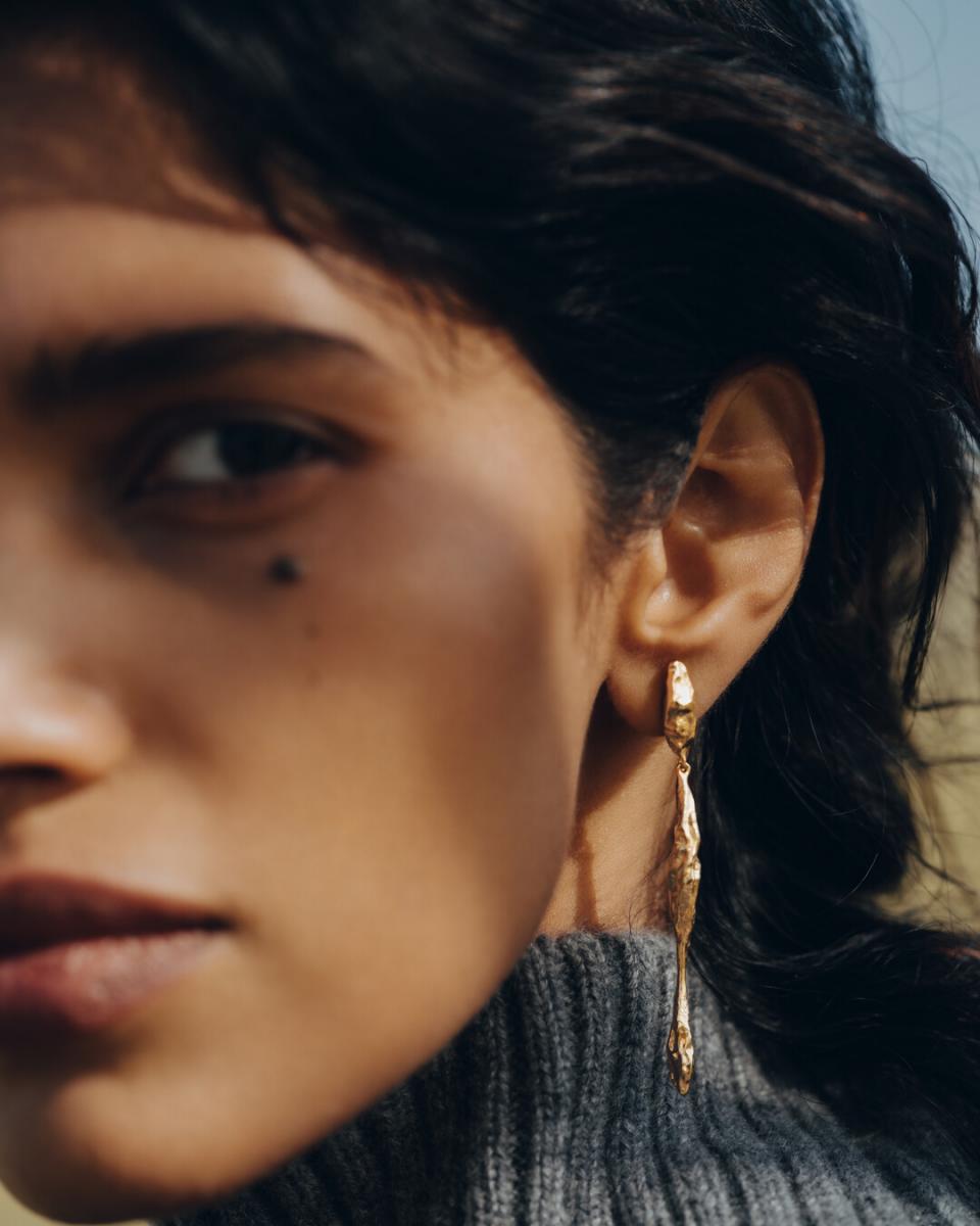 Polène金色長型耳環，搭配毛衣、長捲髮。