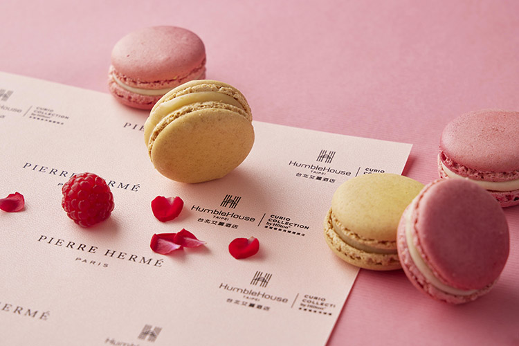 提到Pierre Hermé，自然不能錯過被譽為「甜點界畢卡索」最經典的代表作—馬卡龍（Macaron）。本次午茶組收錄兩款人氣口味：「ISPAHAN玫瑰荔枝與覆盆子馬卡龍」，融合花香、果香與果酸層次，像是一場法式花果盛宴；而「百香果馬卡龍」則以酸甜果香勾勒熱帶氣息，酥脆外殼搭配柔滑內餡，每一口都是幸福的重量。