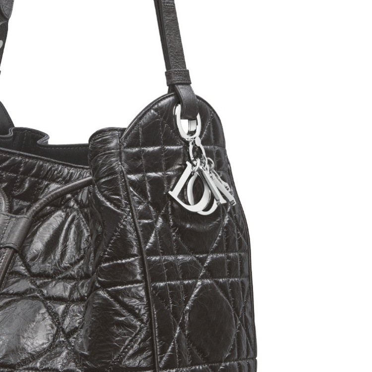 除了籐格紋外，D-Motion這款包上還有品牌最具代表性的吊墜裝飾，這個源自於 Lady Dior 包款上經典的「D-I-O-R」金屬吊飾，是品牌優雅與幸運精神的象徵。靈感來自 Christian Dior 對珠寶與護身符的熱愛，吊飾以鍍金、琺瑯或水晶等材質製成，隨包款移動輕輕搖曳，增添靈動氣質。