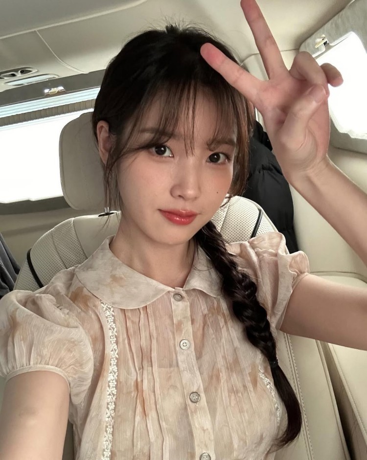 IU將頭髮以低側辮編成長辮，營造鄰家女孩的甜美印象，妝容則以自然色調為主，凸顯清透膚質與淡雅氣息。