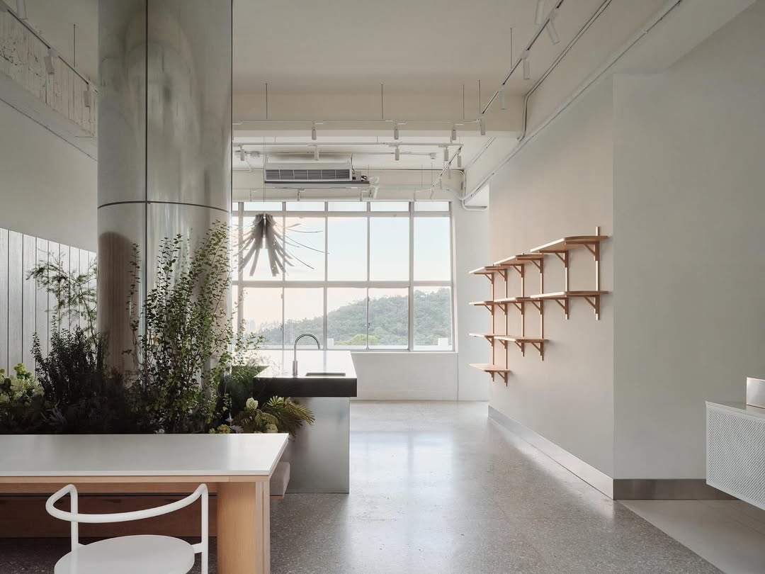 挑高設計搭配頂層鋸齒狀屋頂與大片拱形玻璃窗,窗外山景與自然光匯入室內,為整體空間注入靈動綠意與輕盈氣息。