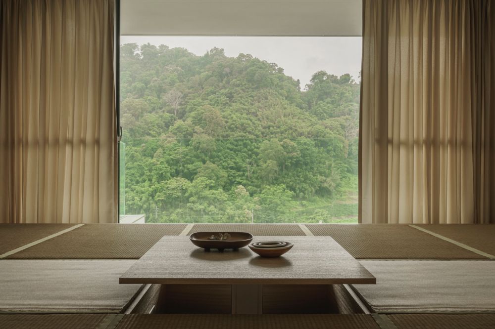 餐廚區的中島與餐桌設計，讓家人圍聚在共享的料理空間，天花板高度與材質錯落，區隔不同空間功能而不設實體隔間，地坪與扶手線條垂直延伸，連貫視覺語境，營造整體性的空間印象。