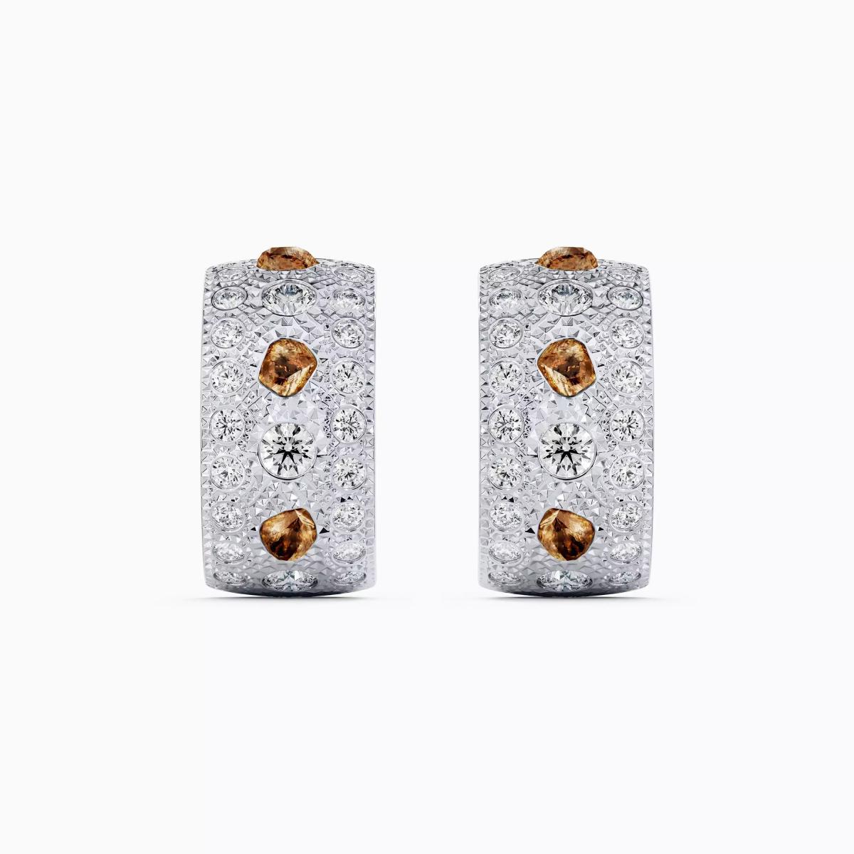 De Beers Talisman 耳環以18K白金為基底,寬度達8毫米,設計核心在於鑽石的多元表現。拋光與原石、白鑽與彩鑽交錯,並以鑿點金工鑲嵌,呈現豐富的肌理感。
