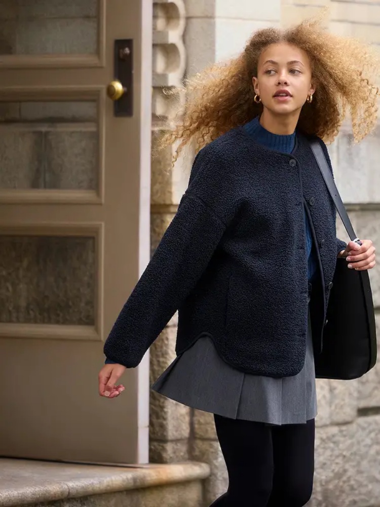 在這套的穿搭中，藉由高腰短裙、內紮毛衣做出高腰短身的好比例，在細節上品牌以黑色外套及黑色內搭褲做顏色呼應，藉由收縮色做出顯瘦效果之餘，同時還能延身形？