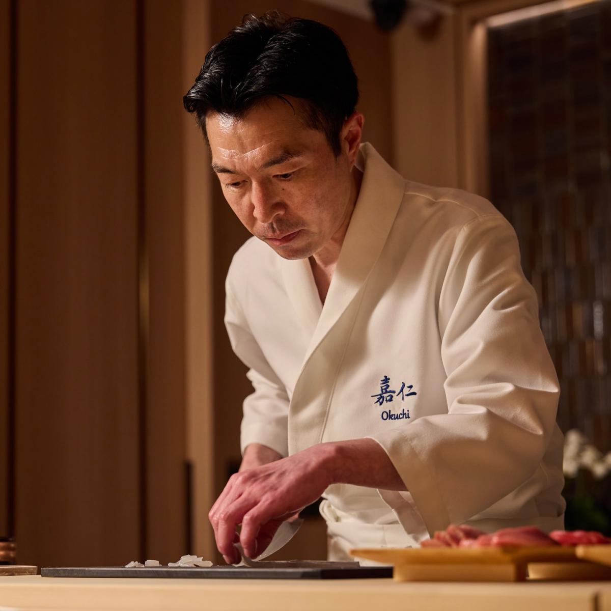 新進榜一星的「鮨 嘉仁」吧檯以臺灣檜木打造,溫潤質感在柔和燈影下更顯雅致,搭配精緻日製漆器,營造純粹且沉靜的用餐氛圍。