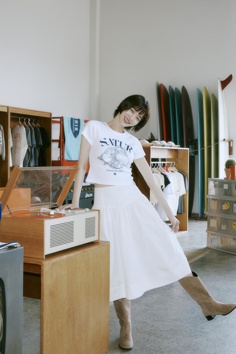 朴圭瑛穿著短版剪裁的白色印花 T-shirt，搭配中高腰設計的白色長裙，立刻拉長了腿部線條，營造出「下身超長」的視覺效果。