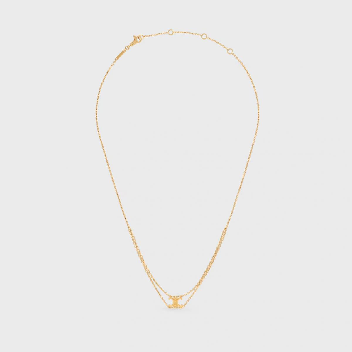 Celine 的 Triomphe Logo，靈感源自巴黎凱旋門的鐵鏈，如今以懸墜的方式被再度演繹。這條 Triomphe Suspended 項鍊以金色飾面黃銅製成，造型簡潔，卻蘊含深厚的品牌故事。