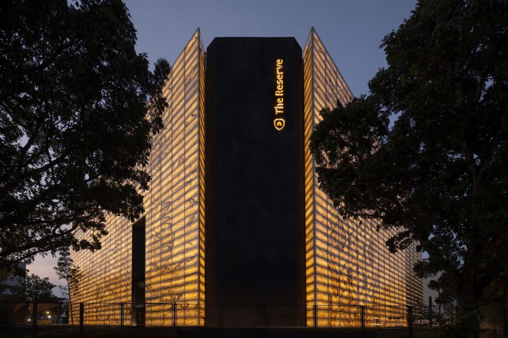 新加坡 MonoLab Studio 的「The Reserve」，將舊電子倉庫改造為貴重資產保管庫，以帶有瑪瑙紋理的夾層玻璃立面，象徵傳統與新興科技的交會，內部則在保留建築形態的同時，透過兩倍高的大門、特殊層架與空間動線等設計，營造戲劇性的氛圍，詮釋保管庫神秘的場域特質。