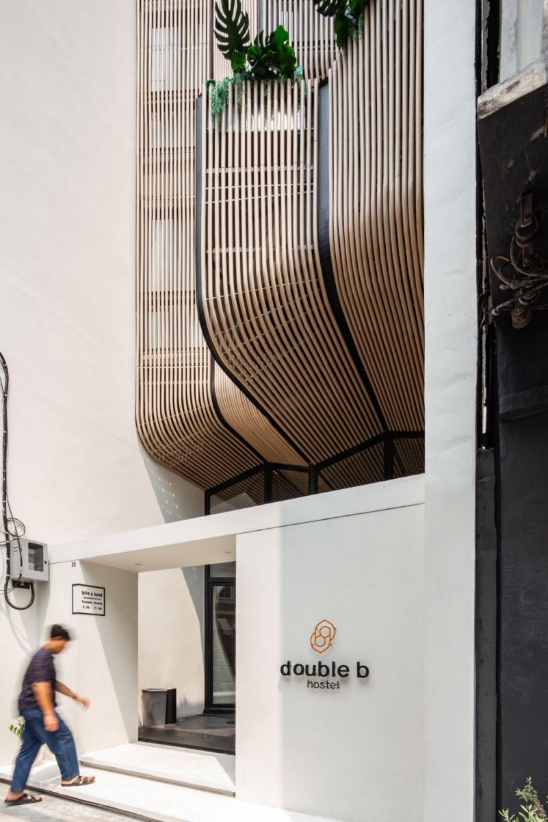 泰國 VMA Design Studio 的「Double B Hostel」，坐落於舊城狹長街廓中，設計團隊結合在地材料、傳統木作工藝與現代工法，創造出具流動感的木質立面，並結合開放中庭巧妙引入自然光與通風，打造融合在地文化與交流氛圍的獨特休憩空間。