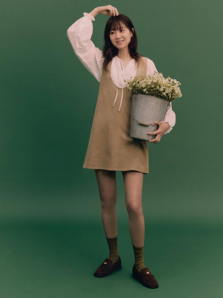 這套造型的亮點，在於淺卡其短洋裝版型俐落，挖領設計拉長肩頸比例，疊搭蓬袖綁帶白襯衫，營造出柔美又乾淨的層次感。