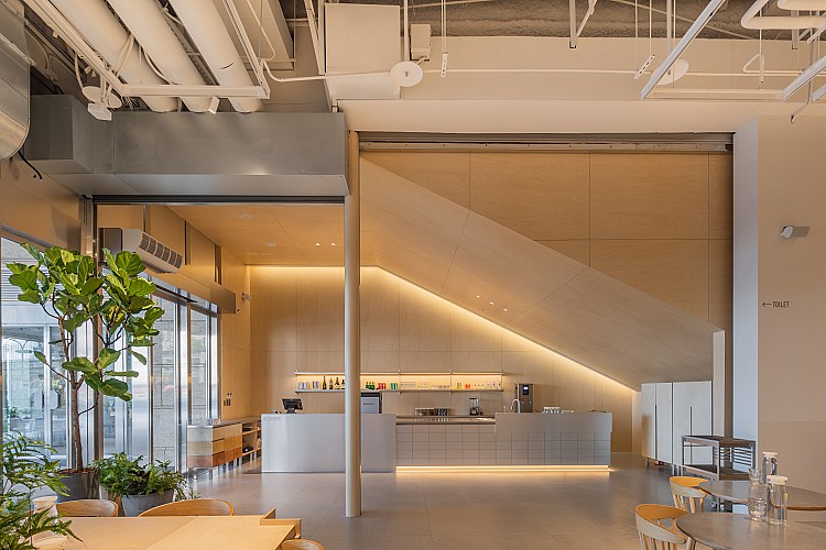 板橋店由彡苗空間實驗操刀設計，以「Urban Patch 城市補丁」為概念，挑高四米的空間裡，灰階磚材、木質元素與綠植交織出冷暖對話，中央植栽島更將都市與自然縫合成一片綠洲。