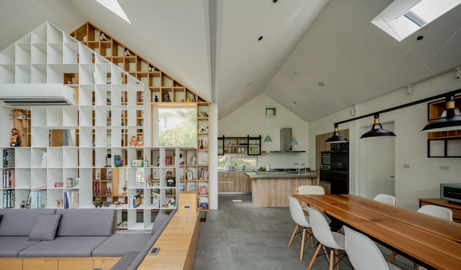 在材質挑選上，設計師嘗試注入更豐富的視覺性，從山形的書櫃、不鏽鋼的金屬、溫暖的木質調，再到沉穩的石地板，搭配不同的空間機能，提供豐富的居住環境。隨著時間推移，夜幕低垂之際，小屋內也點亮了一盞盞明亮的燈光，讓光線穿梭於樹林之間，顯得格外詩意。沿著山丘緩緩經過綠地，每一處都藏著設計驚喜，彷彿一座森林之屋，湧入恬靜氛圍。