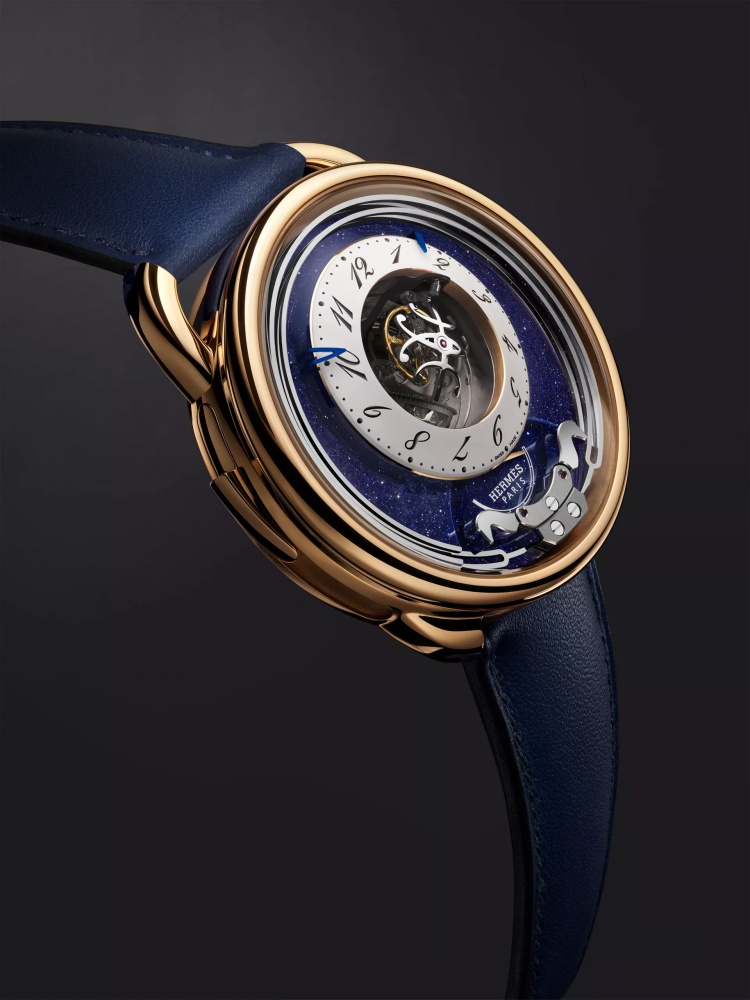 Hermès 愛馬仕 Arceau Duc Attelé 陀飛輪三問腕錶，將高級製錶工藝與馬術精神結合，呈現中央「三軸陀飛輪」與「三問報時」兩大複雜功能之美。錶盤上打造成駿馬形象的音錘；透過音錘擊打細長音叉形的淬火鋼音簧，進行時、刻、分報時，發出如教堂鐘聲般的樂音。