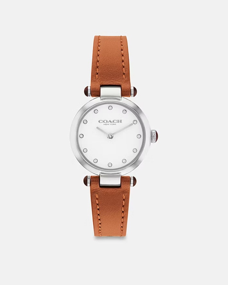 Cary 的魅力在於「剛剛好」——不過度裝飾，也不失高級質感。不鏽鋼錶殼搭配細緻皮革錶帶，潔白錶盤上點綴水晶時標，如星光閃爍般優雅。它的設計平衡了經典與摩登感，既能搭配正裝，也能襯托休閒造型。