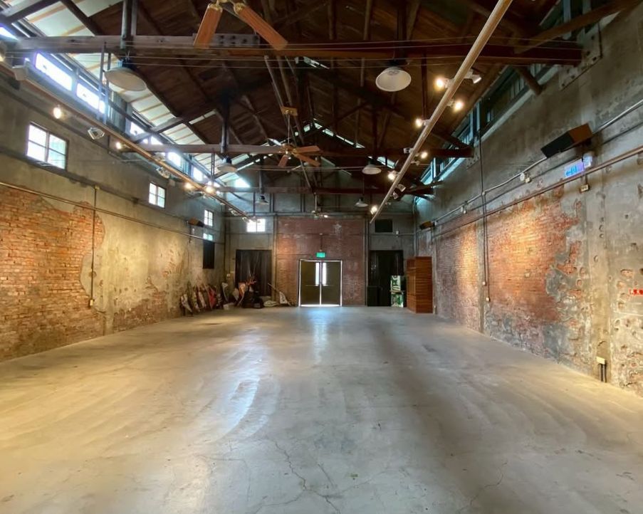 建築師卓卿泉尊重此空間原貌,保留木造屋架、斑駁紅磚、水泥牆的斷痕、通風小氣窗與鑄鐵小窗。這裡不以華麗裝飾取悅,而是讓自然天光灑落,讓觀者在光影與作品之間,找到一份親切與自在。倉庫雖換上新招牌,卻依舊承載著稻田的香氣,提醒人們它始終屬於農業新港。