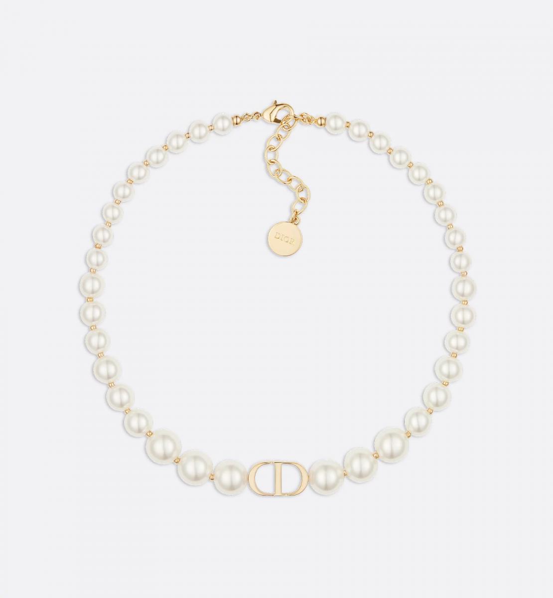 Dior 30 Montaigne 短項鍊以金色飾面金屬串連白色樹脂珍珠，小巧的 CD 標誌成為亮眼焦點。靈感來自品牌位於蒙田大道30號的巴黎總店，象徵經典與新意的交會。頸鍊式設計勾勒出俐落線條，散發一種既優雅又具現代感的女性力量，是專為懂得平衡柔軟與堅定的女人而生。