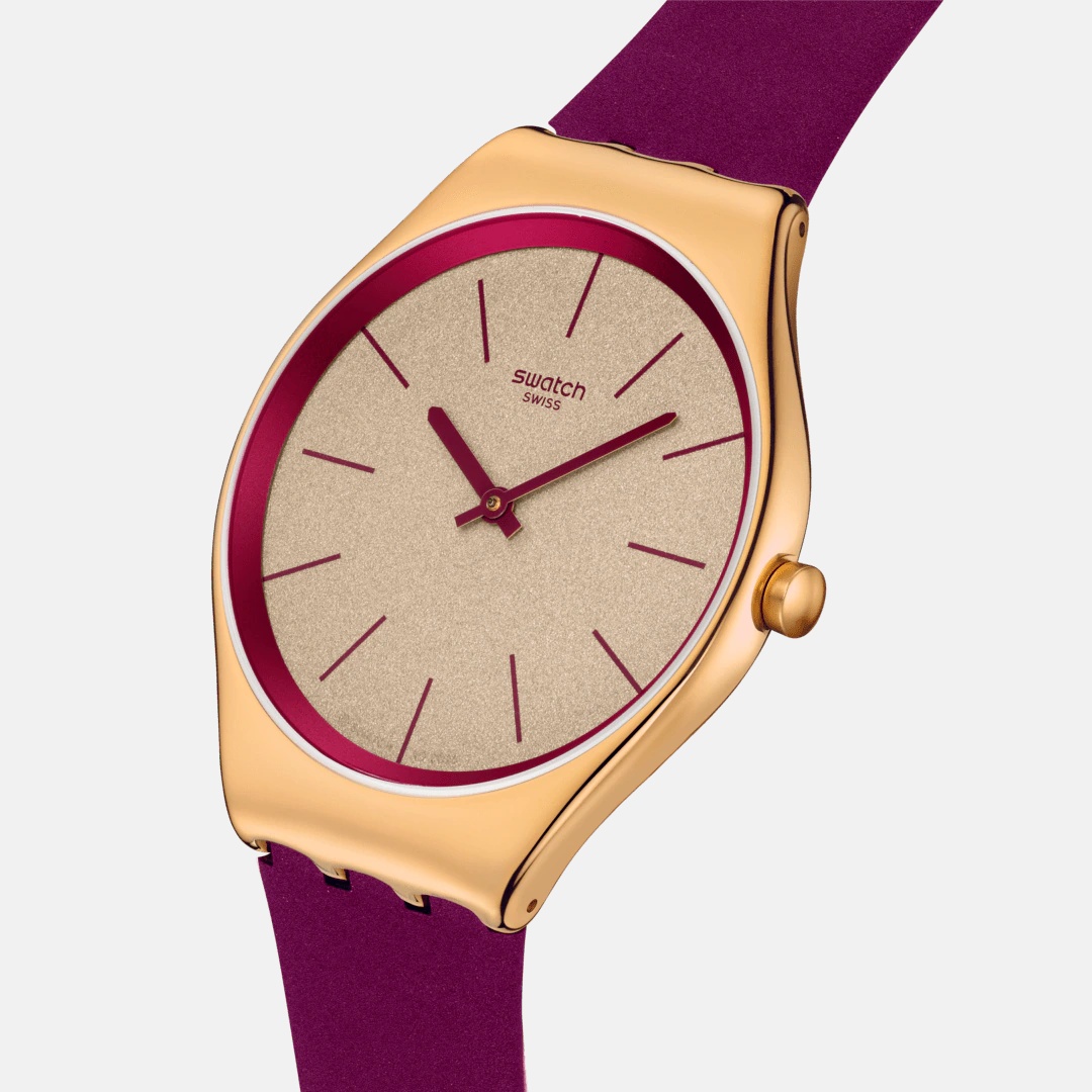 這只 Swatch 全新推出的 Alpine Berry 超薄腕錶，就像冬季果實般鮮明甜美。金色閃耀錶盤搭配莓果紫色錶帶，形成強烈卻和諧的對比。超薄設計使它貼合手腕，配戴舒適無負擔。玫瑰金不鏽鋼錶殼反射出柔和光澤，簡約的線條讓人一眼就感受到 Swatch 的年輕態度。它不是嚴肅的腕錶，而是一種心情的配件——讓時間變得可愛、輕盈、帶著玩味。