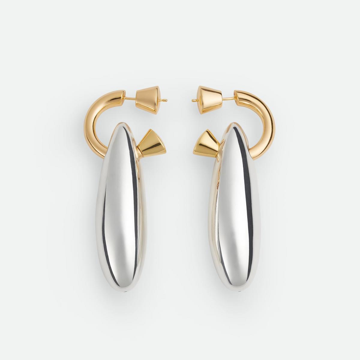 Bottega Veneta 的 Ellipse 大耳環，以極簡線條展現雕塑感之美。銀與金的雙色對比宛如光與影的對話，在光線下反射出低調的奢華。細長的橢圓形廓線修飾臉型，無論短髮或盤髮都能拉長比例。這是一款屬於「冷靜派優雅」的耳環，展現出乾淨、俐落、不言而喻的時髦。