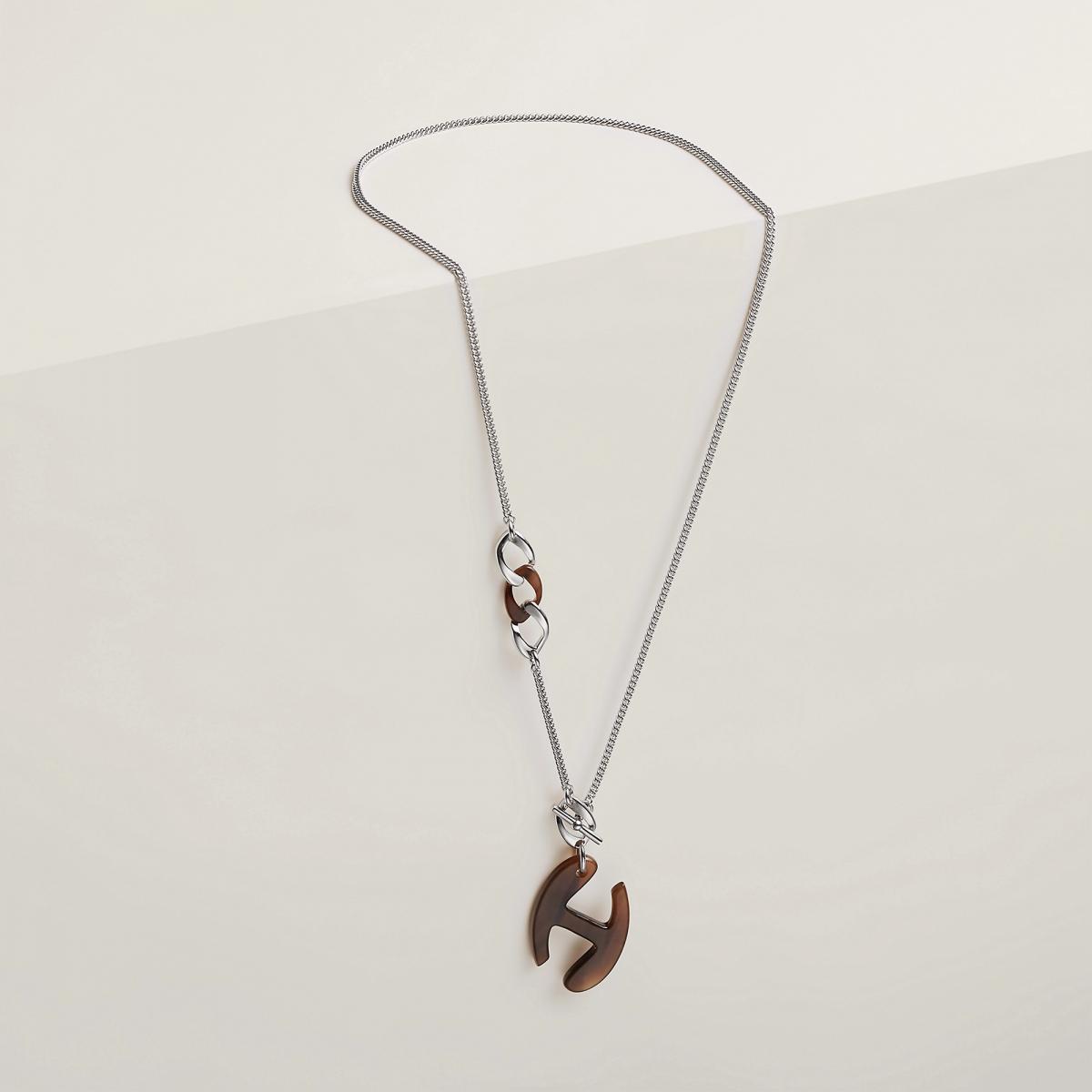 愛馬仕的經典 Chaine d’H 系列，本就是品牌馬具精神的延伸。這款結合牛角與銀色金屬的設計，像是將時間的溫度與金屬的冷靜融為一體。設計靈感取自品牌典藏的馬勒鍊條，H Nautique 元素經重新詮釋，柔中帶剛。可調節的圓環設計讓它能一飾兩戴：繞頸成短鍊時俐落摩登，拉長成垂墜造型時又帶出隨興藝術感。天然牛角紋理讓每一條項鍊都獨一無二，既低調又極具存在感，讓你輕鬆打造出張曼玉自然不造作的慵懶時尚。