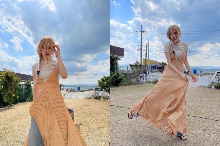 這套仙氣滿點的混搭造型，把度假感和街頭感融合得恰到好處。以柔和蜜桃色的百褶吊帶洋裝作為主角，裙擺隨風掀動的輕盈質地，內搭簡約奶油白踢，削弱洋裝的正式感，增添一點清新俏皮的日常味道。