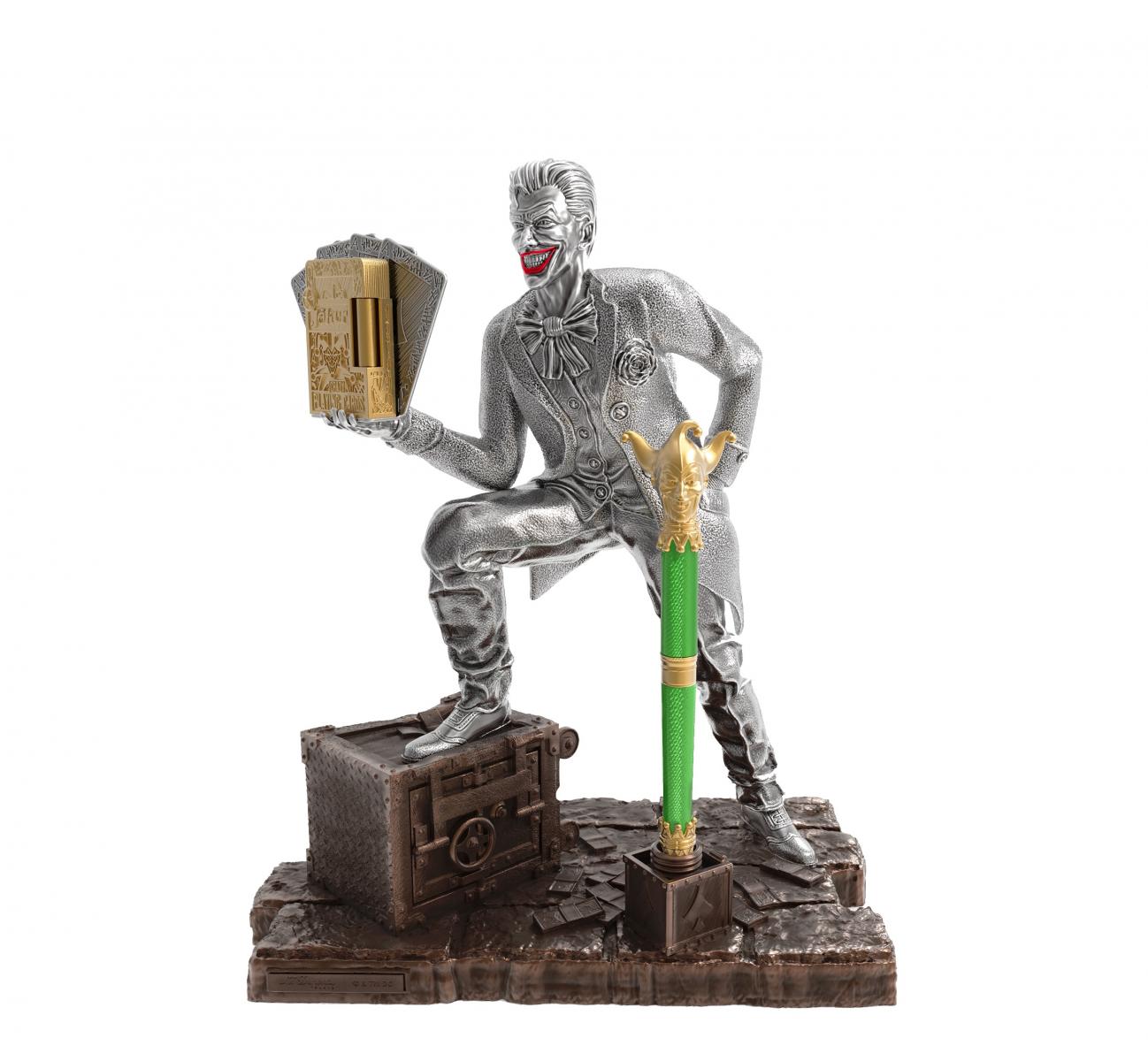 S.T. Dupont 與 DC 合作，以小丑為靈感打造高訂收藏組：銀色雕像捕捉 Joker 招牌的瘋狂姿態，手中握著刻有撲克牌圖騰的 Ligne 2 打火機，腳邊則是保險箱造型底座。綠漆鋼筆以小丑帽造型筆尖與黃金飾件呈現反派標誌性色彩，整組宛如從電影場景走出的奢華藝術品。
