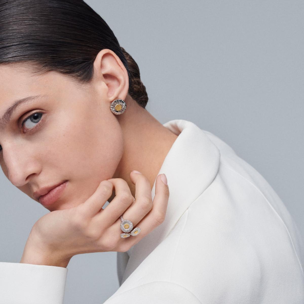 如果你第一次接觸 Buccellati，這對雛菊耳環絕對是最能體會品牌「金屬也能很柔軟」的代表作。乍看之下，你可能以為耳上的花瓣是銀絲細線堆疊而成，實際卻是純銀經過一刀一刀雕刻，讓原本堅硬的金屬呈現出類似布料纖維的立體細紋。這種獨特肌理，是 Buccellati 經典工藝語言的縮影。直徑2.5公分的尺寸不算迷你，但佩戴起來意外輕巧，視覺上更像一束被陽光照亮的小花停在耳畔。中心的金色花蕊替耳環增加了亮點，也讓整體更活潑、耐看。無論是白襯衫、丹寧外套或夏日洋裝，它都能讓穿搭多一點「會呼吸的輕盈感」。 