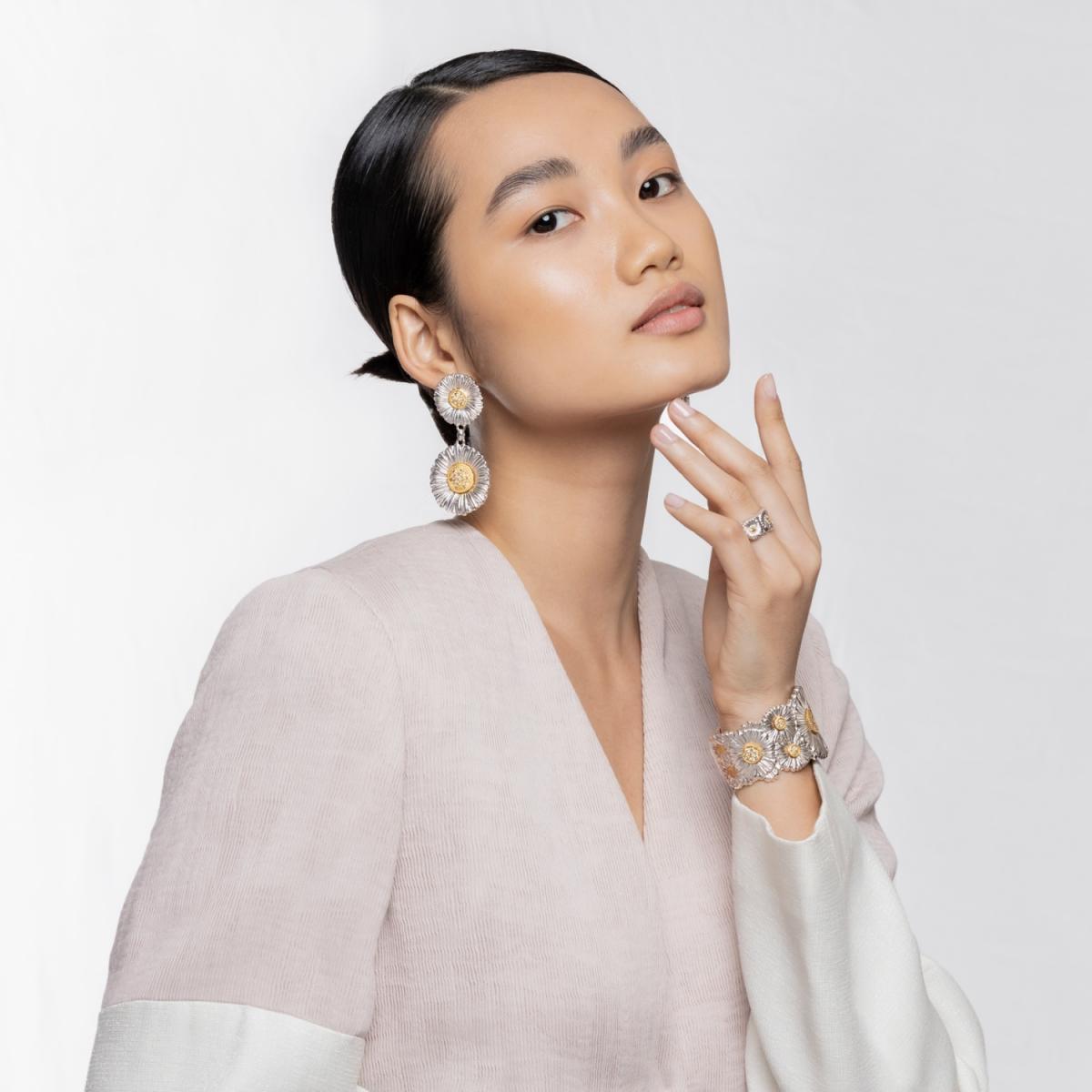 最後這款吊墜耳環，是整個系列中最有「律動感」的一款。上方小雛菊直徑1.6公分、下方大雛菊直徑2.5公分，並以5.1公分的總長度打造出優雅又俏皮的垂墜效果。走路時耳環會微微晃動，像一朵朵在陽光下輕輕搖曳的小花，非常迷人。雖然是純銀製品，但因為中心的金色花蕊與立體雕刻，整體看起來依舊非常立體、亮度自然。它有一種清新不造作的魅力，無論是什麼風格的穿搭，都能直接提升精緻度。如果說單朵耳釘是日常款，那麼這款吊墜就是「約會款」——自然、明亮、帶著朝氣，讓你一戴上，整個人都變得更柔、更亮了些。