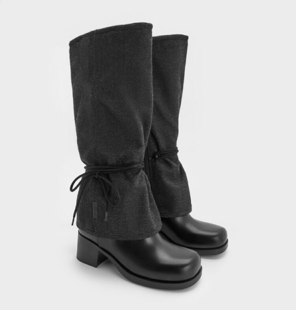 對稱綁帶造型勾勒出俐落骨架，深灰色調低調沉靜，混材質鞋面展現粗跟長靴的細膩層次感。