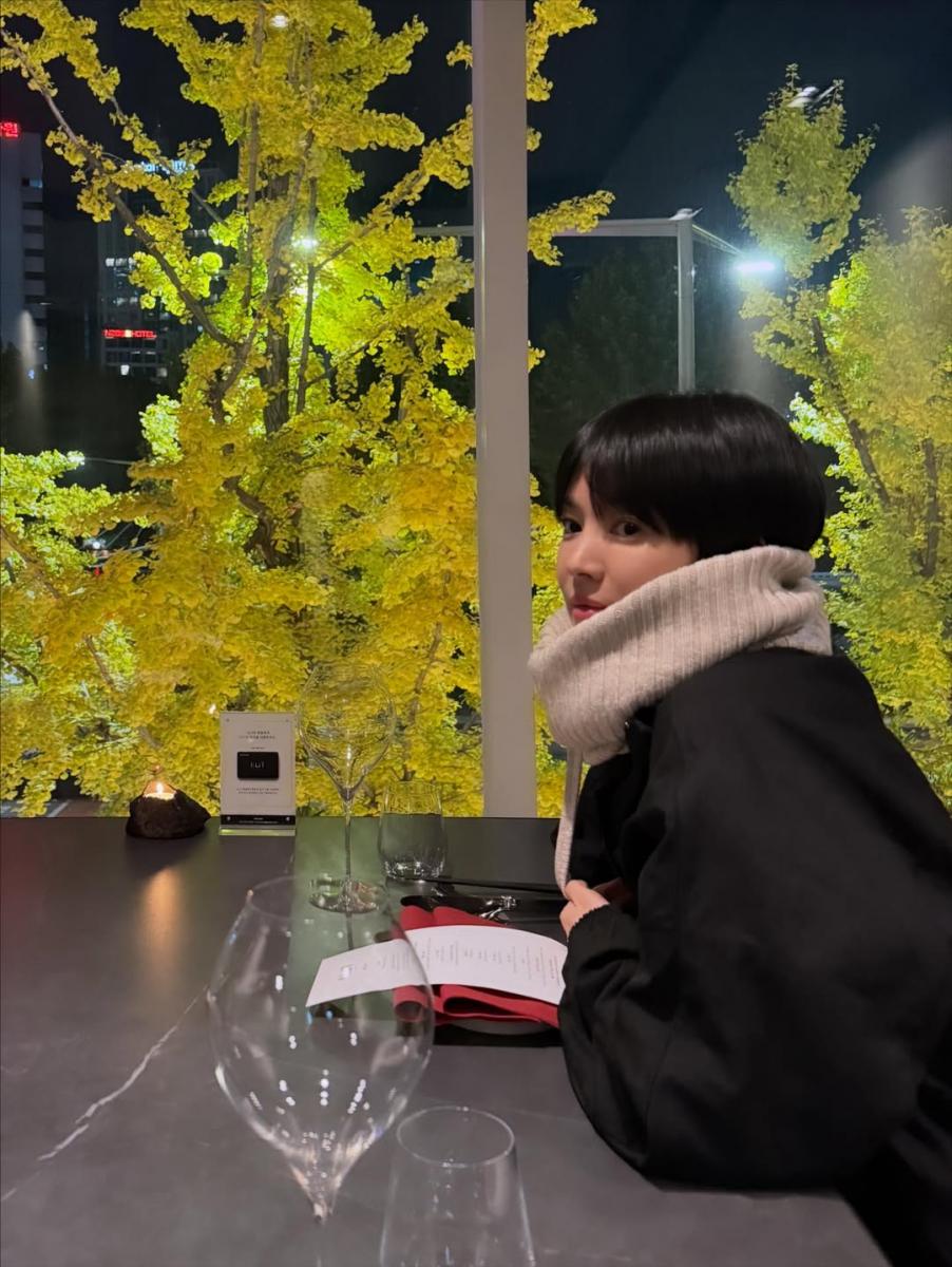 簡約的米色針織套頭毛衣搭配深色外套，整體配色低調，卻因材質對比而顯得層次分明。柔軟的針織為造型注入溫度，也讓臉部線條看起來更柔和；深色外套則穩住整體輪廓，使穿搭不流於過度休閒。宋慧喬刻意避免繁複裝飾，讓視覺焦點回到材質本身，呈現一種安靜卻耐看的成熟感。這樣的搭配不追求明顯的年輕符號，而是透過簡潔與舒適感，讓整體看起來從容、有精神，是非常適合輕熟女日常借鑑的穿搭公式。