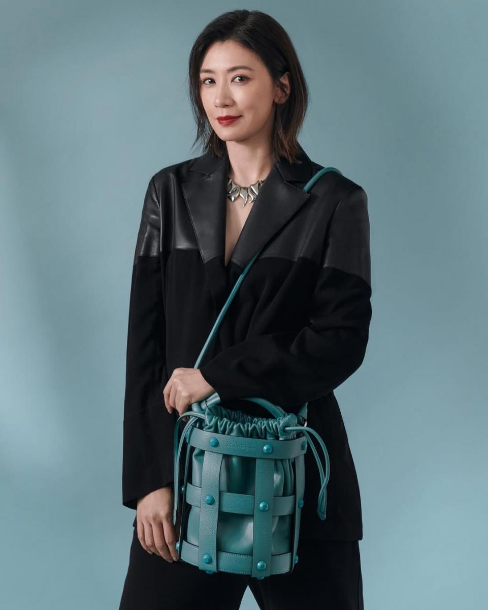 這套造型的關鍵，在於西裝本身就具備足夠的層次。異材質拼接讓原本偏正式的黑色西裝多了一點變化感，不必靠繁複搭配就能成立。賈靜雯刻意讓內搭保持簡潔，將視覺焦點留給剪裁與材質轉換，再以線條俐落的銀鍊項鍊作為收尾，為造型注入現代感與個性；手上則拎著 Ferragamo 於2022春夏推出的 Cage Bag 水桶包，結構感鮮明的設計為整體增添時尚張力。這樣的穿法不強調年齡，也不刻意柔化輪廓，而是透過設計細節讓整體看起來更輕、更有態度，是成熟女性非常耐看的減齡方式。