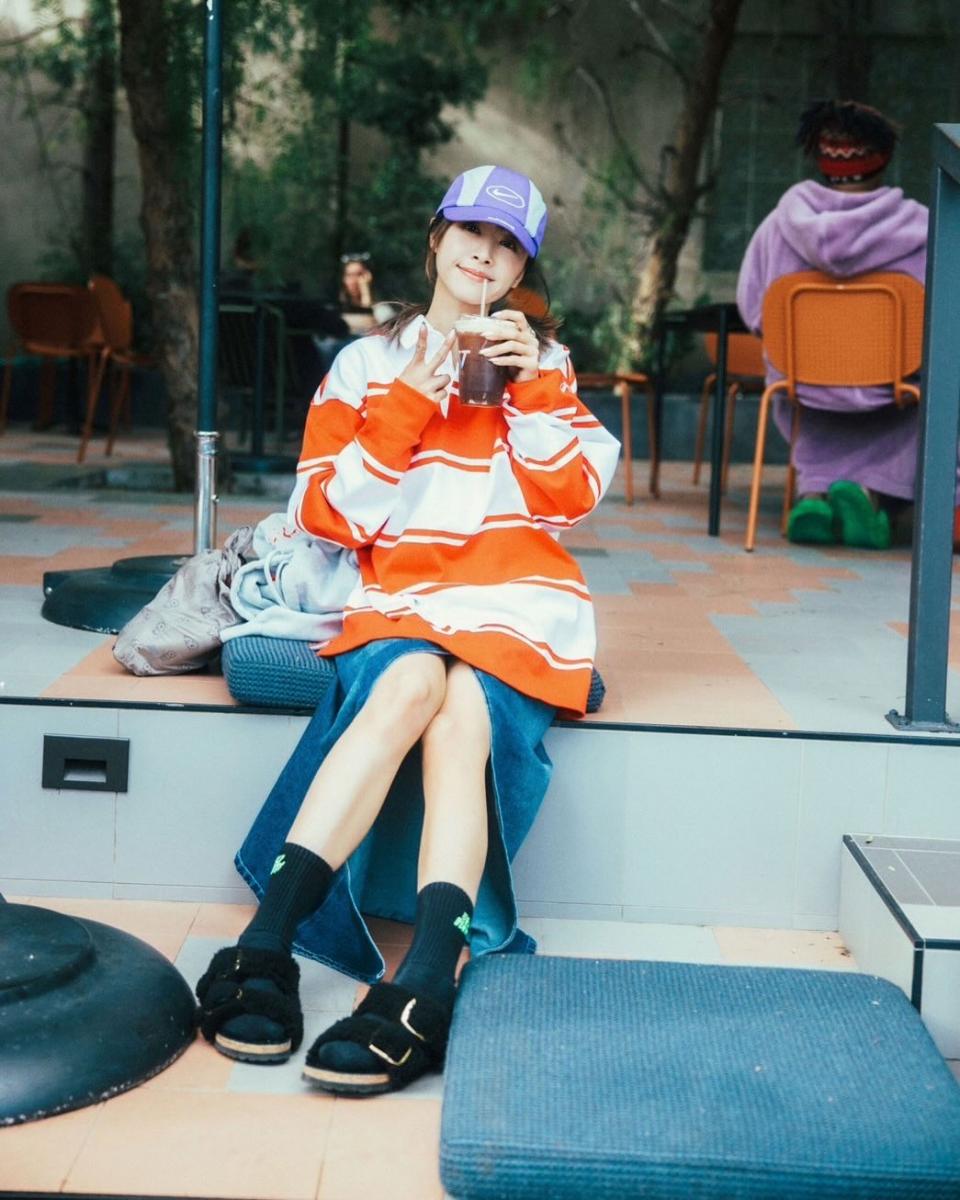 蔡依林這套造型把「可愛」與「休閒」拿捏得恰到好處。紅白條紋上衣以寬鬆版型營造童心氛圍，顏色明亮卻不刺眼，讓整體看起來自然有精神；下身選擇丹寧開衩長裙，透過開衩設計露出腿部線條，替休閒造型加入一點輕盈節奏，也避免長裙帶來的厚重感。運動涼鞋與中筒襪的搭配，刻意保留街頭感與生活氣息，讓這身穿搭不走精緻路線，而是更貼近日常。這種把比例、材質與潮流風格混搭在一起的方式，正是讓造型看起來年輕卻不幼稚的關鍵。