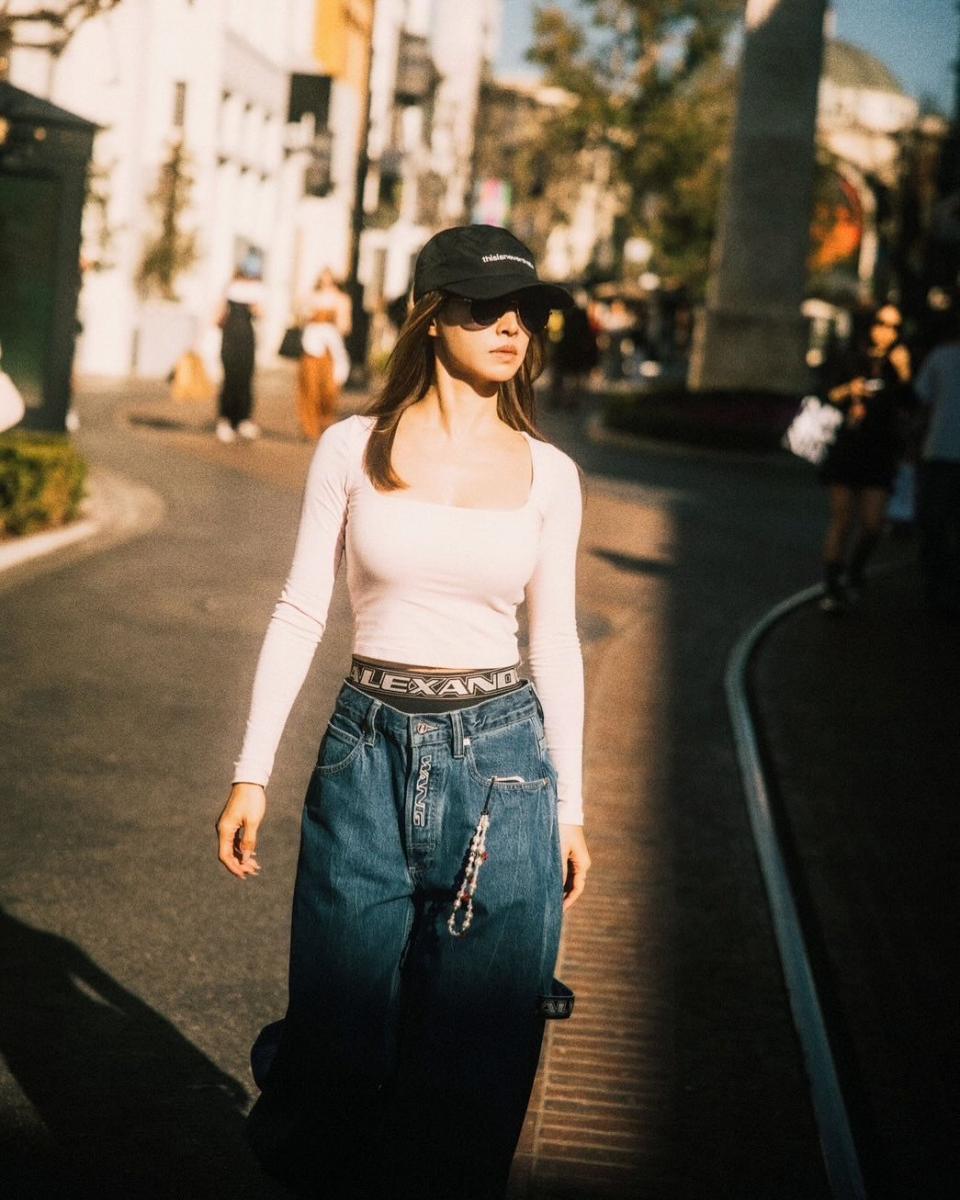 這套造型的關鍵，在於對身形比例的精準掌控。短版上衣貼合上身線條，讓視覺焦點自然上移，卻不刻意強調性感；高腰內搭微微露出，像是一道隱約的分界線，巧妙拉長下半身比例，也為造型增添街頭感層次。丹寧寬褲以鬆弛輪廓平衡上身的俐落，讓整體線條看起來自在、不緊繃。棒球帽與墨鏡的加入，進一步中和女性化輪廓，讓這身穿搭在柔與酷之間取得漂亮平衡。這正是成熟街頭風最聰明的搭配方式，不是穿得更少，而是把比例穿對。
