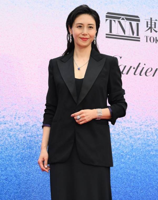 為了對抗歲月帶來的身形變化，松嶋菜菜子在私服中偏好運用硬挺剪裁來重塑精神面貌。正如此套穿搭所示，她完美平衡了「大膽用色」與「俐落廓形」，巧妙以一件高飽和的寶藍色拼接西裝，打破深色系的沉悶，藉此鮮豔色調瞬間提亮氣色，展現出不刻意裝嫩的飽滿活力。而在下半身的選擇上，她則利用高腰闊腿褲優化比例並延展視覺腿長，營造出隨性大氣的從容感。 